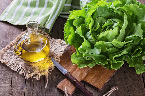 Butter lettuce and oil over wooden rustic background stock photo