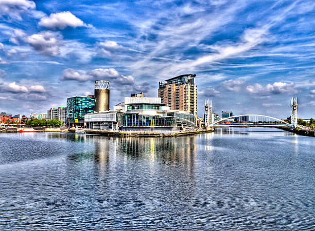 MediaCityUK on Salford Quays Salford, United Kingdom - June 22, 2014: MediaCityUK waterfront mixed-use development site in Salford Quays during sunny day, viewed from Media City Footbridge. Blue sky with several clouds.  bbc photos stock pictures, royalty-free photos & images