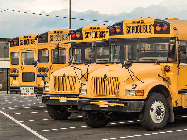 istock Four Yellow School Buses Parked in a Lot. 484495826