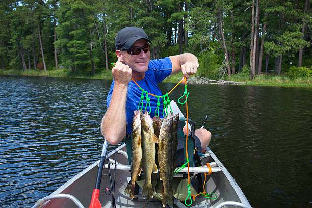 rybak w canoe posiada się z walleyes stringer - catch of fish sport black and white activity zdjęcia i obrazy z banku zdjęć