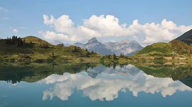 Forest, mountains and summerclouds mirroring in lake Trubsee. Summer scene in the Swiss Alps.