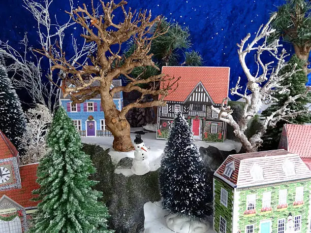 Photo showing some model card houses, made by using my own printable design.  The houses have been cut, folded and assembled to become part of a landscaped Christmas village display, complete with tiny trees and snowmen.