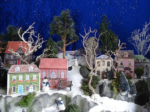 Photo showing some extremely charming model houses, made using homemade printable designs.  These miniature paper houses are part of a much larger Christmas village display, which features mountains, trees and a blue sky made from velvet material, along with silver glitter to represent the twinkling stars at night.