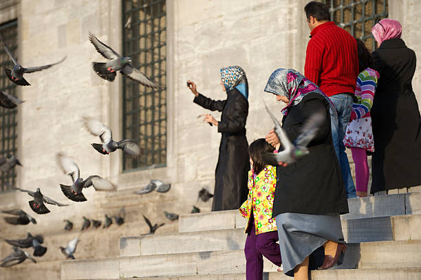 Istanbul, Turkey - May 5, 2010: Families with children leave a mosque amid a flurry of pigeons. Religion plays an important role in modern Turkey.