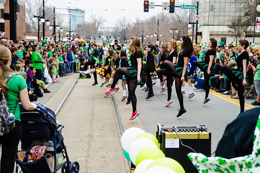 Little Rock, Arkansas, USA - March 15, 2014: A group of irish dancers performs during a stop in a St. Patrick's day parade. The dancers are various ages from young adults to children. Spectators are on both sides of the street.