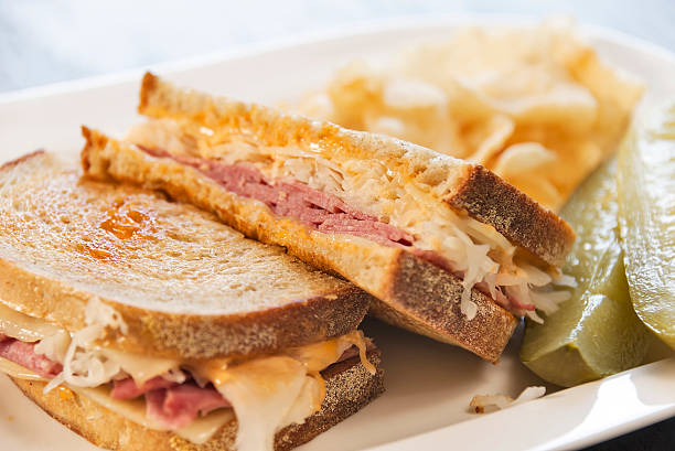 Deli style grilled Reuben sandwich A grilled delicatessen style Reuben sandwich served with dill pickles and potato chips. reuben sandwich stock pictures, royalty-free photos & images