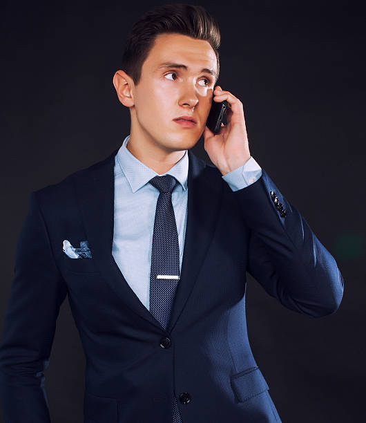 istock young pretty business man standing on black background, modern hairstyle 484517420