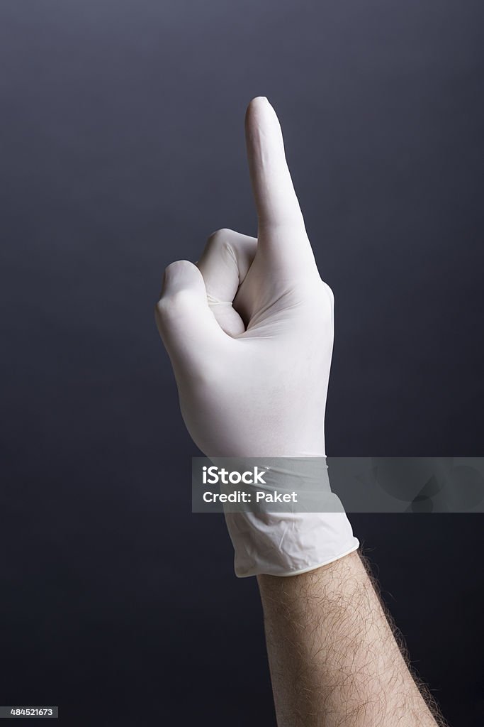 Male hand in latex glove - finger up Male hand in latex glove (finger up) on dark background Adults Only Stock Photo