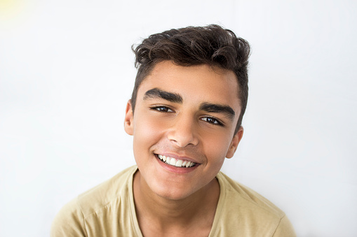 Portrait of laughing young man against white background. Man wearing casual clothing and standing against white background. Horizontal composition. Image developed from Raw format.