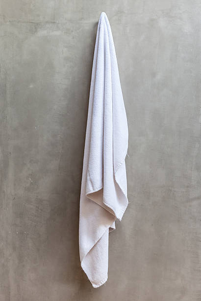 istock White towel is hanging on a hanger with concrete wall. 484535038