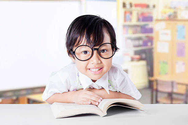 istock Cute little student reading literature in the class 484539456