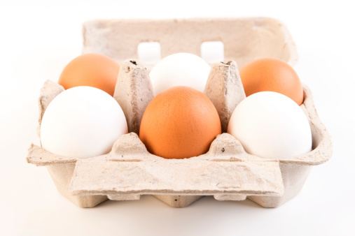 Six brown and white eggs in a cardboard container made of three white and three brown eggs