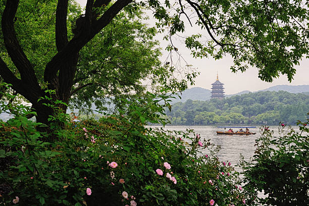 Hangzhou, China - April 24, 2015. Tourists riding on small boat in West Lake with Leifeng Pagoda in background, Hangzhou, China. Hangzhou is the capital city of Zhejiang Province, China, attracting lots of tourists for its beautiful scenery and richness in historic sites.