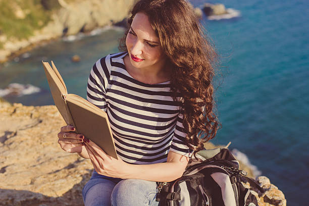 istock Beautiful woman is reading book on the rock peak 484545588