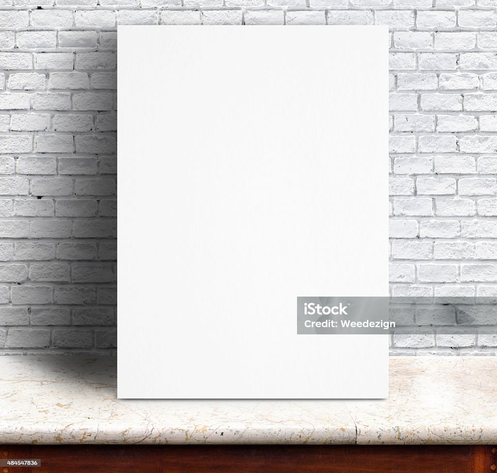 White paper poster lean at brick wall and marble table Black White paper poster lean at white brick wall and marble table,Template mock up for adding your text. Leaning Stock Photo