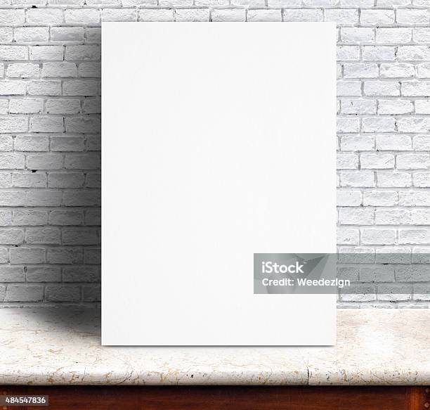 White Paper Poster Lean At Brick Wall And Marble Table Stock Photo - Download Image Now