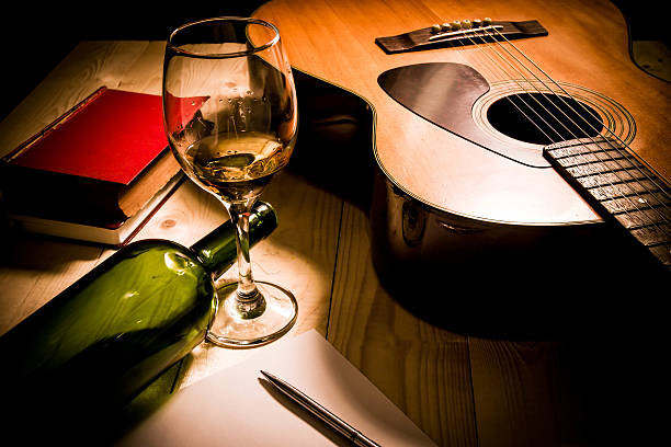 Guitar with Red Book and Wine on a wooden table.