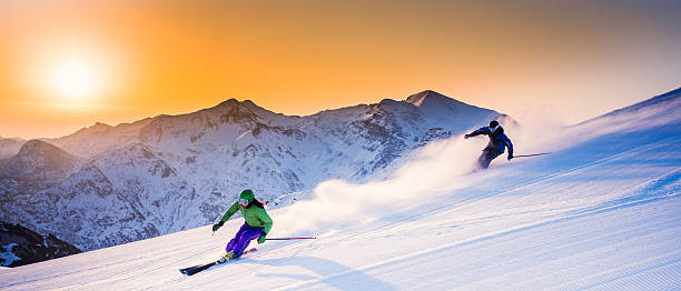 Alpine Skiing Panoramic shot of two alpine skiers in high mountains at early morning. extreme skiing stock pictures, royalty-free photos & images