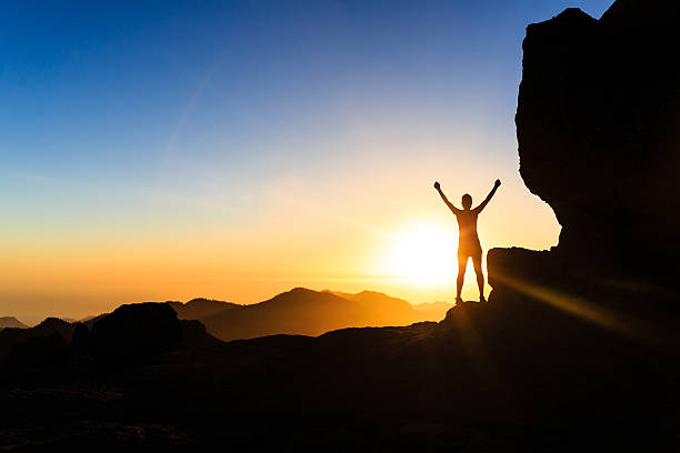 Woman climber success silhouette in mountains, ocean and sunset stock photo