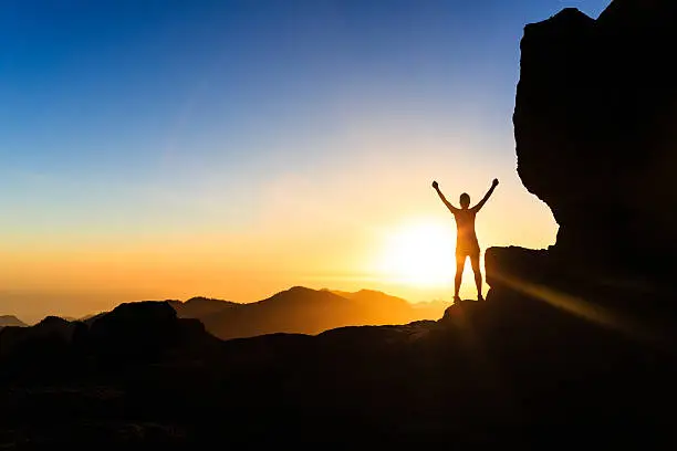 Photo of Woman climber success silhouette in mountains, ocean and sunset