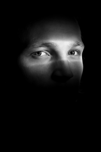 Portrait of a young man in the shadow, only partly visible.