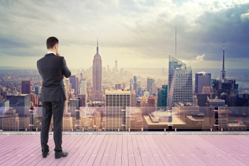 businessman standing on roof and looking at new york