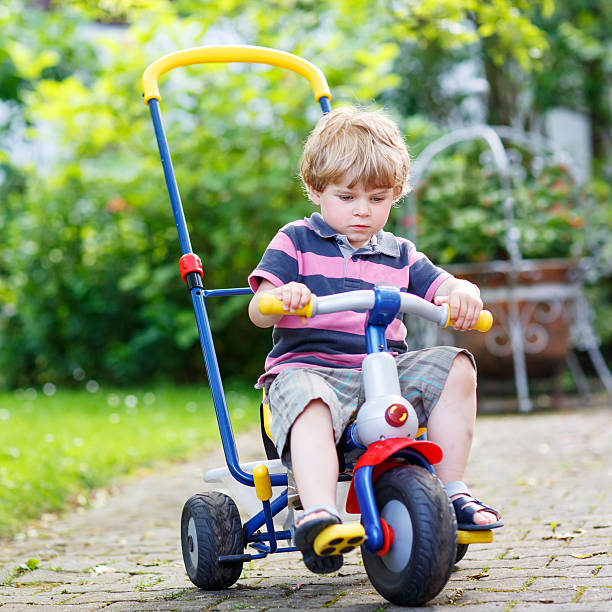 istock Active blond kid boy driving tricycle or bicycle 484563548