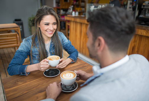 Couple on a date having a cup of coffee at a cafe and looking very happy