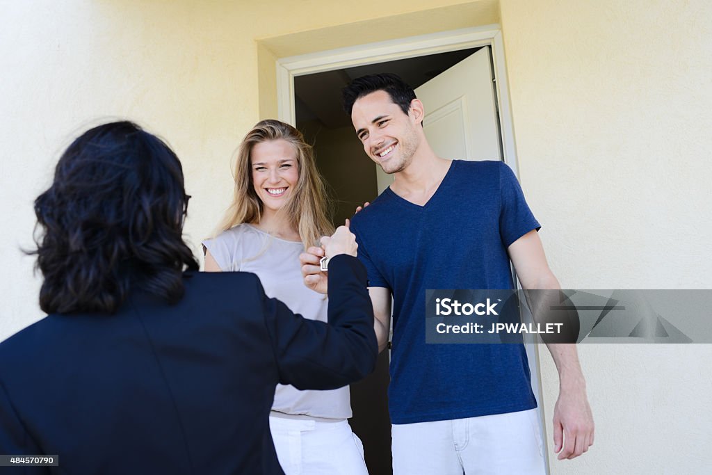 young couple with real estate agent getting new house key happy young couple with a real estate agent getting keys in front of their new house 2015 Stock Photo