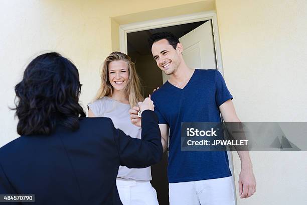 Young Couple With Real Estate Agent Getting New House Key Stock Photo - Download Image Now