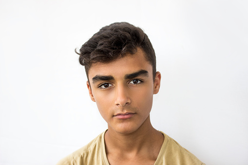 Close-up portrait of young man with blank expression. Young man standing isolated on white looking at camera with blank expression. Horizontal composition. Image developed from Raw format. Teenage boy wearing casual clothing.