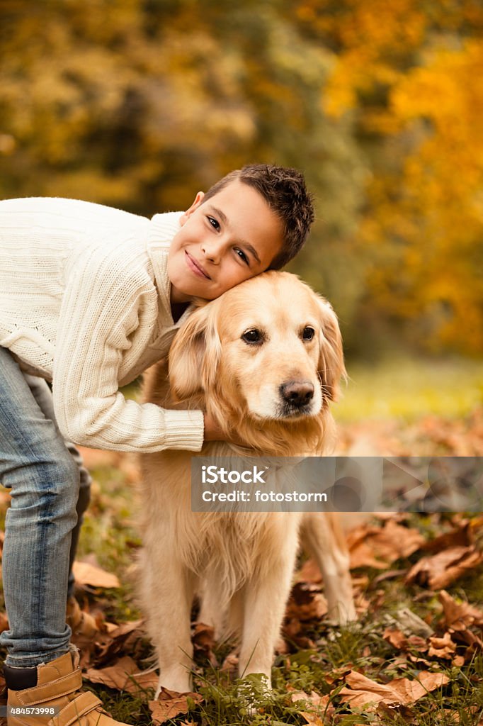 Boy embracing his dog in the park Little boy embracing his dog, Golden Retriever, in the park. Autumn Stock Photo