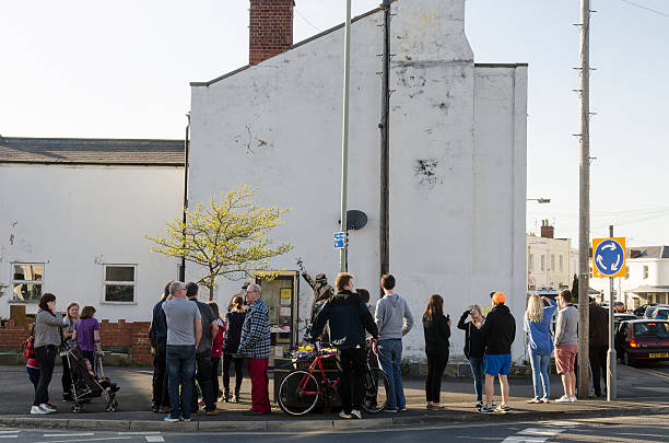 Crowds gathered around a possible Banksy artwork, Cheltenham Cheltenham, United kingdom - April 13, 2014: Crowd gathered around a possible Banksy graffiti artwork that appeared overnight on the side of a house in Cheltenham. It depicts three government agents monitoring phone conversations from a public phone box.  banksy stock pictures, royalty-free photos & images