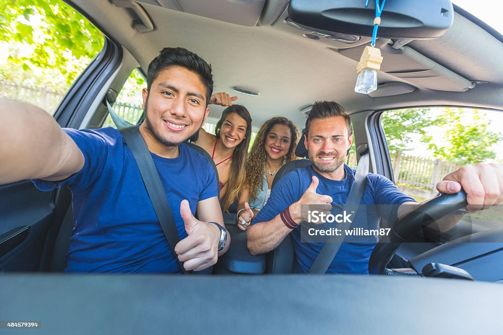 Group of friends taking a selfie into the car Group of friends taking a selfie into the car before leaving for vacations. They are a mixed race group of four persons, two caucasian and two hispanic. Car Stock Photo