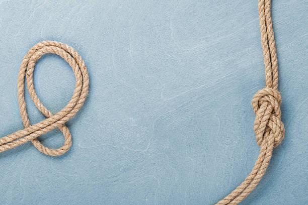istock Ship rope knot on wooden texture background 484582059