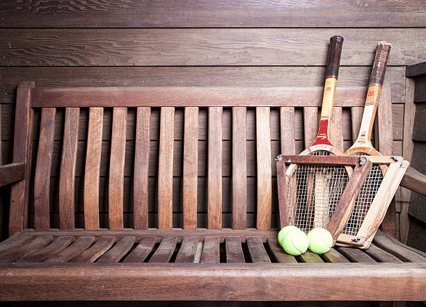 Tennis Racquets San Diego, CA, USA - August 13, 2015: Vintage Wilson Tennis Racquets with ball on bench. Wilson is the world's leading manufacturer of ball sports equipment. It is located in Chicago USA with over 1600 employees worldwide. The Chris Evert wood tennis racquet is the model shown from the 1970s. She is a former number one professional tennis player with 18 Grand Slam singles titles. wimbledon seats stock pictures, royalty-free photos & images
