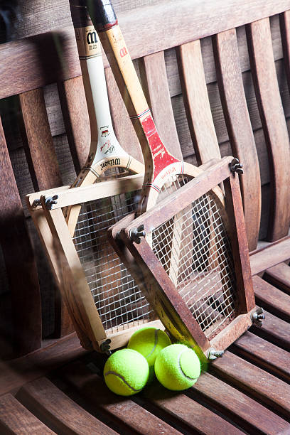 Vintage Tennis Racquets San Diego, CA, USA - August 13, 2015: Vintage Wilson Tennis Racquets with ball on bench. Wilson is the world's leading manufacturer of ball sports equipment. It is located in Chicago USA with over 1600 employees worldwide. The Chris Evert wood tennis racquet is the model shown from the 1970s. She is a former number one professional tennis player with 18 Grand Slam singles titles. wimbledon seats stock pictures, royalty-free photos & images