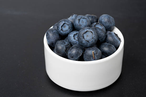 istock white bowl with blueberries on a black background, close-up 484582809