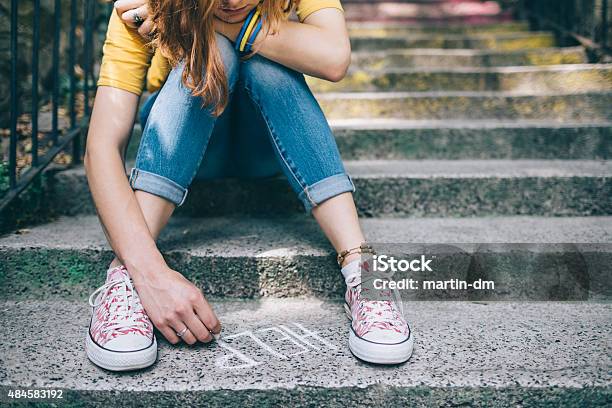 Unahppy Girl Writes Help On The Ground Stock Photo - Download Image Now - Teenager, Sadness, Teenage Girls