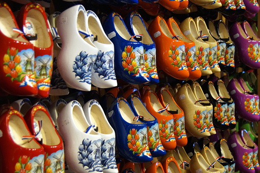 Amsterdam, Holland, 12.12.2022: Traditional souvenir clogs for sale, a must from the Netherlands. Colourful wooden clogs painted with regional motifs. Travel destination background of Dutch tradition.