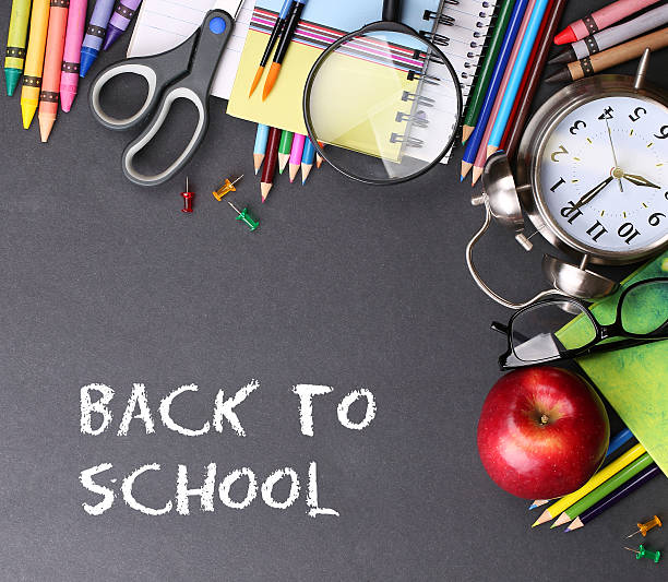 istock Books, apple, alarm clock and pencils on black board background 484588116