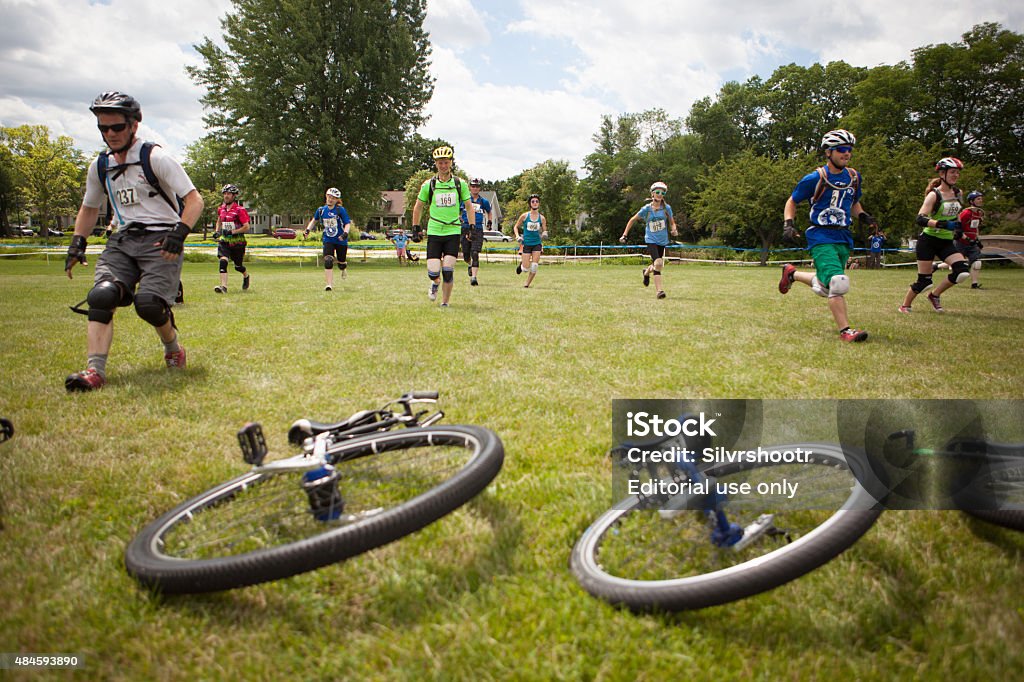 LeMans type start of a unicycle cyclocross race. Madison, Wisconsin USA - August 1, 2015: Starting line chaos as the starting gun fires at the beginning of the Cyclocross portion of the 2015 North American Unicycling Convention and Championships. This is a LeMans type start, where racers have to run 50 meter/yards to get to their unicycles. This helps mix up the field, so that everyone doesn't arrive at the first turn at the same time. Other events during the week of competitions included track, freestyle, cyclocross and others.  2015 Stock Photo