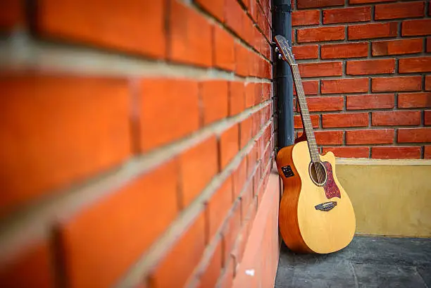 Photo of Guitar with red brick background.