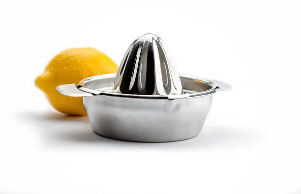 Kitchen Utensils: Citrus Squeezer, chrome citrus juicer with behind it one ripe yellow lemon, isolated on white