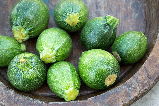 Courgette or round zucchini on wooden plate