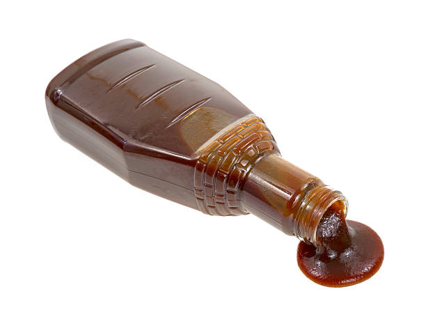 Barbecue sauce spilling A full bottle of barbecue sauce spilling on to a white background. barbeque sauce photos stock pictures, royalty-free photos & images