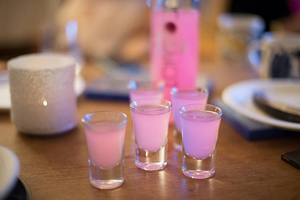 Five shot glasses filled with pink alcoholic beverage at a party.