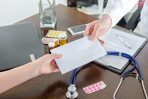 Doctor giving a prescription to his patient in medical office