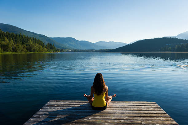 un cadre paisible en bord de lac, posture de méditation au lever du soleil - eau douce photos et images de collection