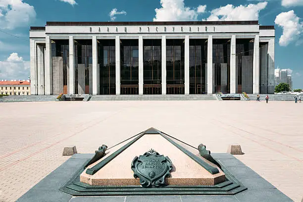 Building Of The Palace Of Republic In Oktyabrskaya Square - Famous Place In Minsk, Belarus. Statue before Palace - Kilometer Zero - iconic sign, designation of zero kilometer road of Belarus